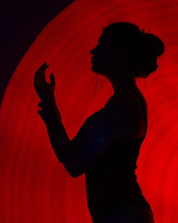 The black silhouette of a woman against a red light.