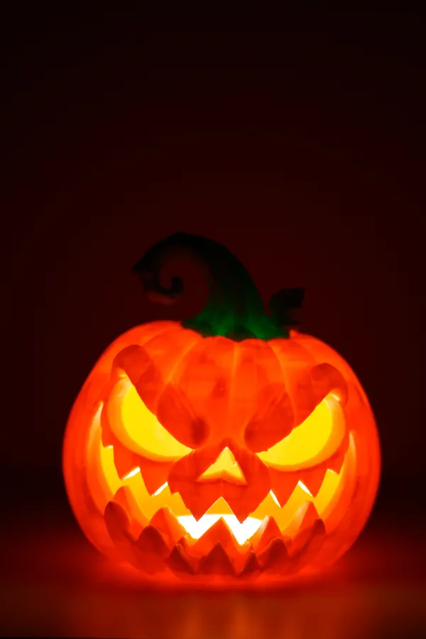 A glowing jack-o'-lantern with an evil grin on a dark red background.