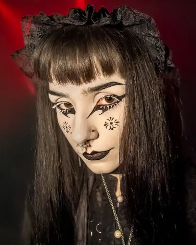 Close-up of a face with sharp black eyeliner, a fringe and small drawn stars on one cheek.